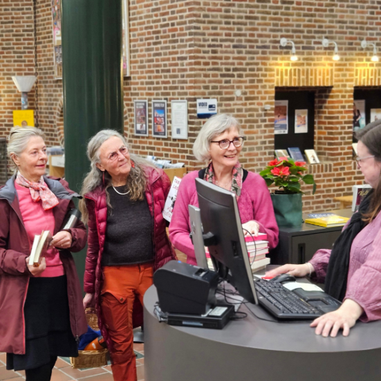 Tre ældre kvinder på biblioteket i Holstebro får hjælp af bibliotekar 