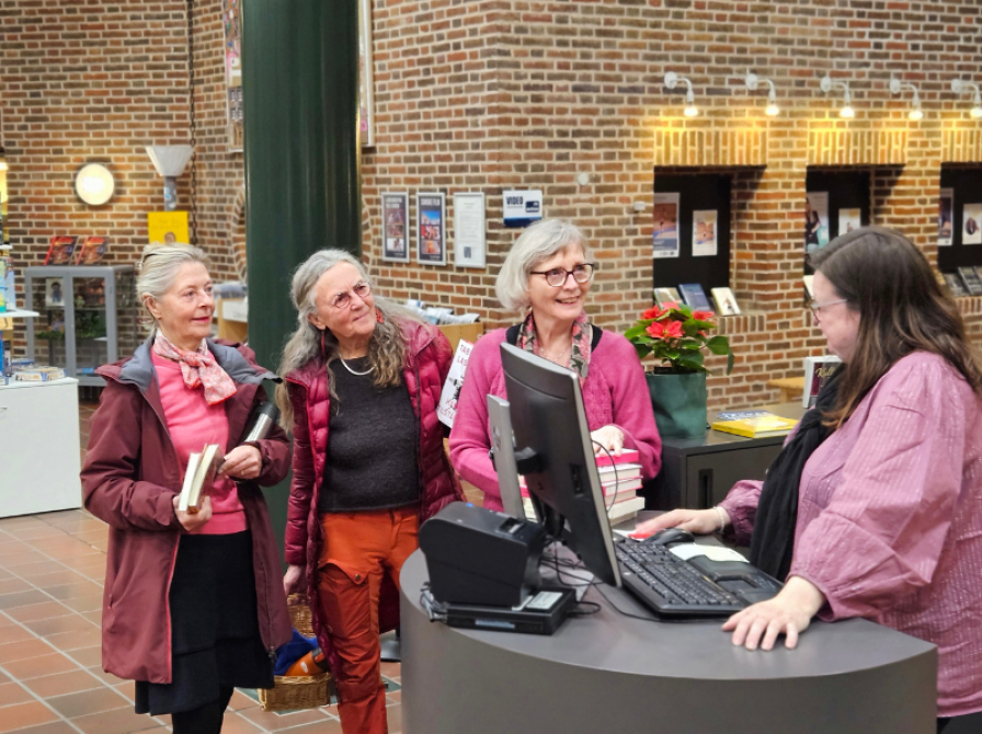 Tre ældre kvinder på biblioteket i Holstebro får hjælp af bibliotekar 