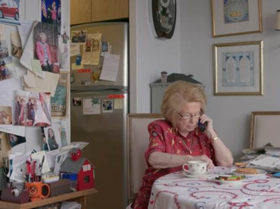 Dr. Ruth ved hendes køkkenbord taler i telefon